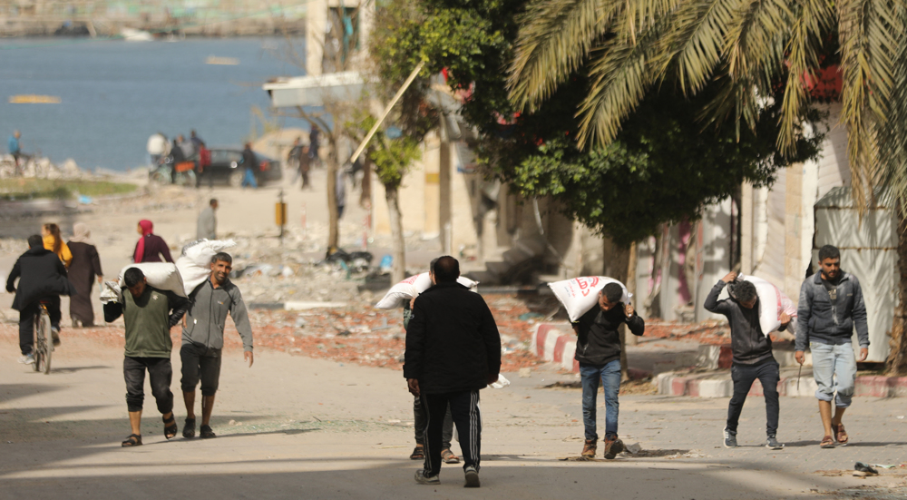 Palestinians rush to collect flour as aid trucks squeeze into Gaza